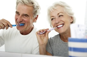Senior couple brushing teeth to care for dental implants