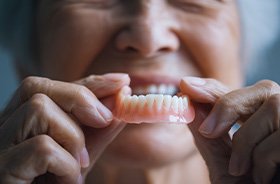 Senior person holding a lower denture