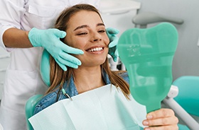 Happy patient admiring her new dental implant restorations