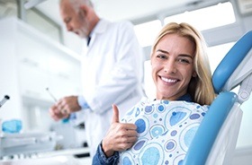 Woman in dental chair giving thumbs up