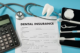 Dental insurance document next to dental instruments