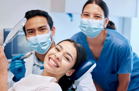 Happy patient posing with her dental team