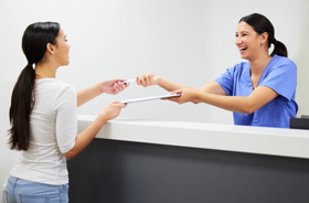 Dental team member handing clipboard to patient