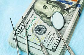 Money and dental tools representing the cost of dental emergencies in New Haven
