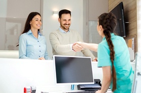 Happy patient shaking hands with dental receptionist after appointment