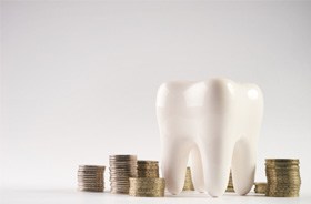 Tooth model next to stacks of coins