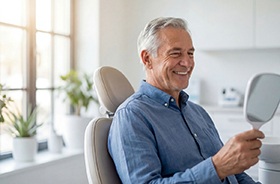 Senior dental patient looking at his smile in mirror