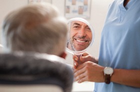 Man looking in mirror, admiring his new restorations