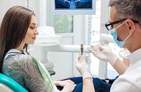 Dentist showing patient an implant model