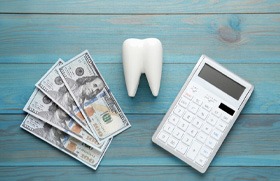 Calculator, tooth, and money arranged on tabletop