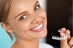 Smiling woman holding Invisalign tray