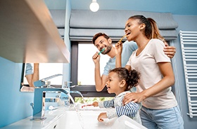 Happy family in front of mirror, brushing teeth