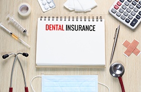 Dental insurance written on notepad, surrounded by other objects