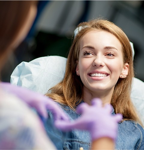 Woman in dental chair smiling at her dentist