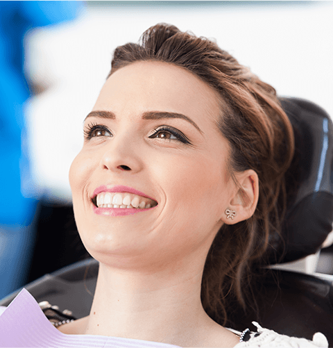 Woman in dental chair leaning back and smiling