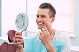 Happy male patient using mirror to admire results of cosmetic treatment