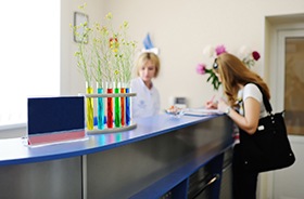 Woman paying for veneers at dental office front desk