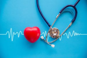 small red heart and stethoscope on blue background