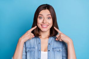 Woman pointing at her bright smile after free whitening in New Haven