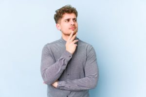 Puzzled man in gray shirt against blue background