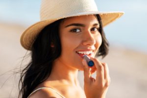 Young woman on beach, applying lip balm