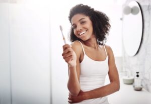 Smiling woman in bathroom, holding toothbrush