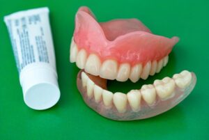 Dentures next to tube of adhesive