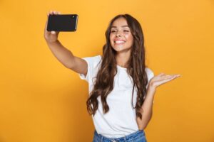 Smiling young woman recording herself with her phone 