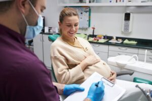 Dentist taking notes while speaking with pregnant patient